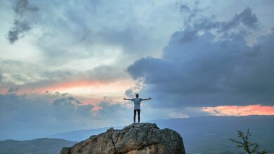 man standing on top of rock mountain during golden hour