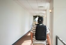 a man walking down a hallway with a backpack on his back