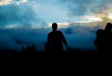 silhouette of person walking towers trees