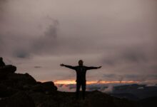 man standing on rock formation under cloudy sky during daytime