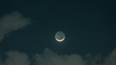 The moon is seen through the clouds in the night sky