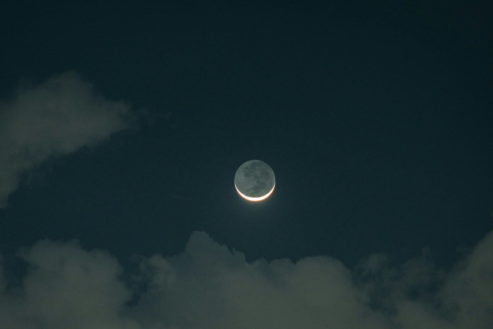 The moon is seen through the clouds in the night sky