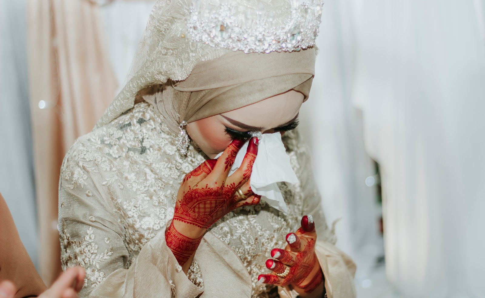woman in beige and white beaded dress holding white tissue
