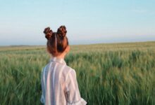 woman in white sweater standing on green grass field during daytime