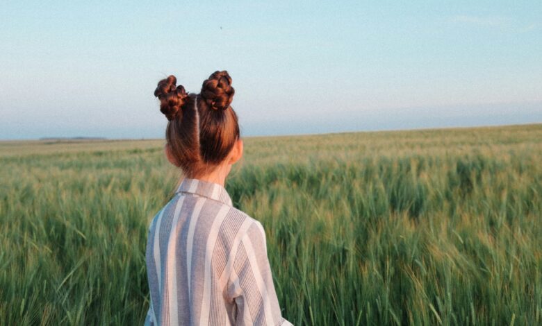 woman in white sweater standing on green grass field during daytime